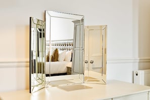 A bedroom with a mirrored wardrobe, a bed with a tufted headboard, and a white dresser. - Stylish Edinburgh Suite in the City Centre (Edinburgh)