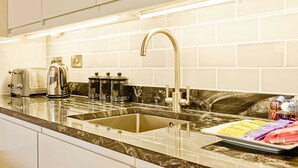 Una cocina moderna con un lavamanos de acero inoxidable, un tostador empotrado y una cafetera.