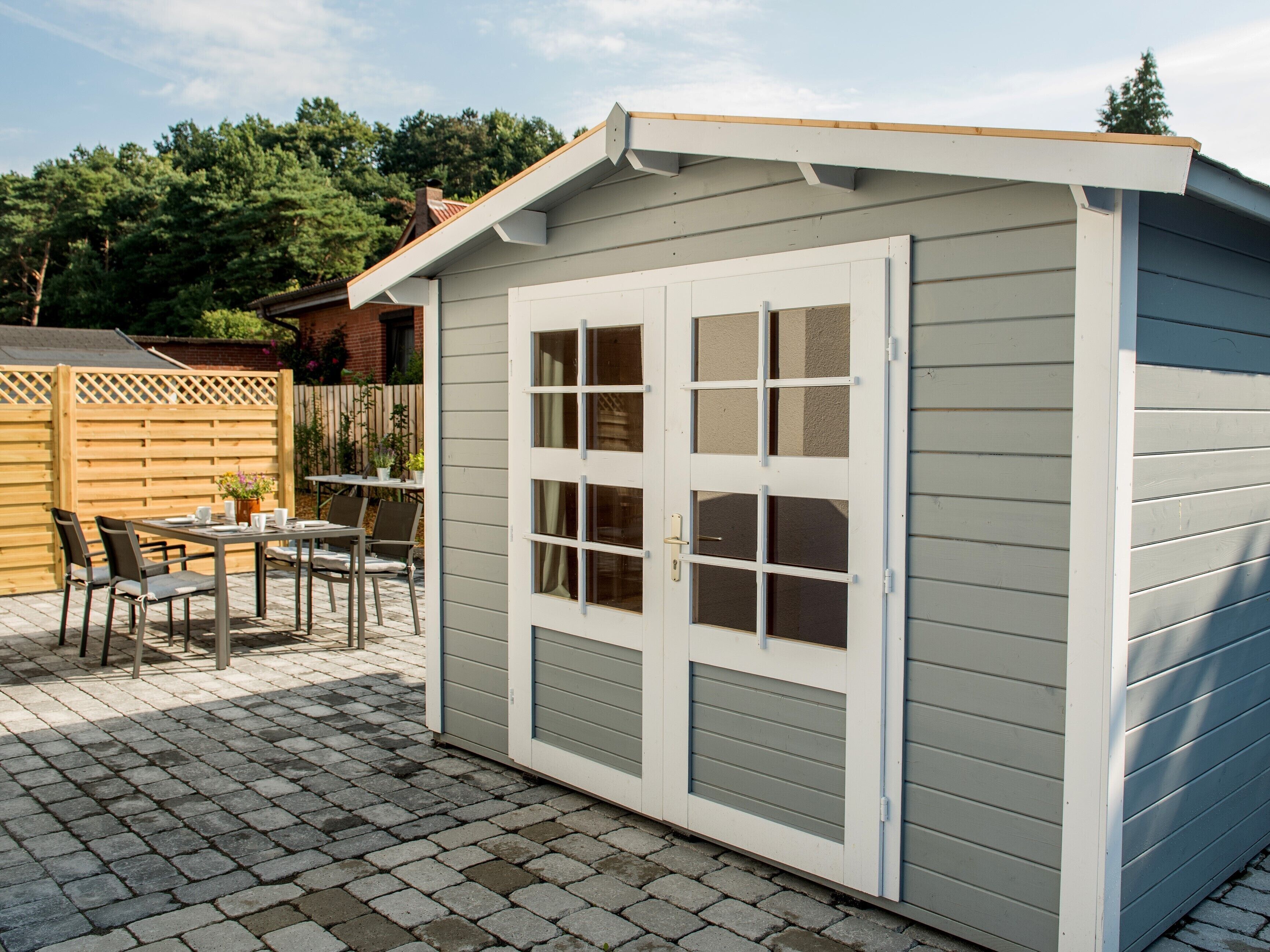 A shed with a sliding door and a small patio area with a table and chairs.