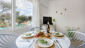 Un comedor con una mesa dispuesta para dos, una botella de vino y vistas de la ciudad.