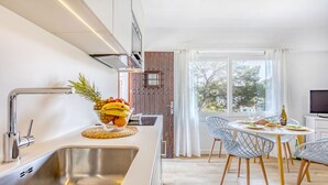 Una cocina moderna con un lavamanos de acero inoxidable, un frutero y una zona de comedor con mesa y sillas.