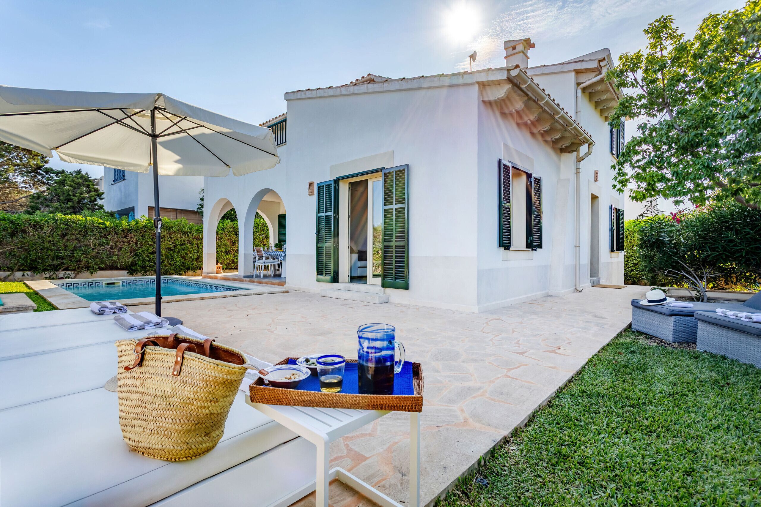 Un espace aménagé au bord de la piscine, avec une table dressée pour un repas, un panier en osier et un plateau de boissons.