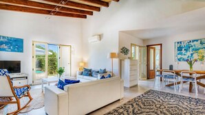 A spacious living room with a white sofa, a wooden rocking chair, and a dining area with a table and chairs. - Can Sivinar by dracmallorca (Santanyi)
