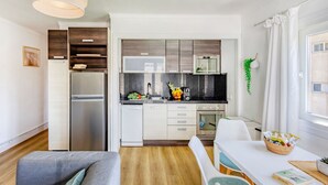 A modern kitchen with built-in appliances, a dining area with a white table and chairs, and a large window with curtains.