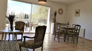 A dining area with a table and chairs, a vase with flowers, and a view through a large window.