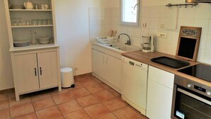 A compact kitchen with white cabinets, a sink, a stove, and a window above the sink.