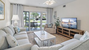 A living room with a sofa, coffee table, TV, and a view of the outside.