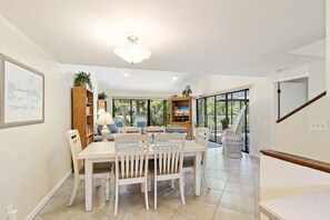 A spacious dining area with a white table and chairs, a wooden bookshelf, and a ceiling fan. - SeaPines, Pet friendly, On site pool and tennis, Golf view (Hilton Head Island)