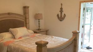 Ein Bett mit hölzernem Kopfteil und Fußteil, ein Nachttisch mit Lampe und ein Wandbild.