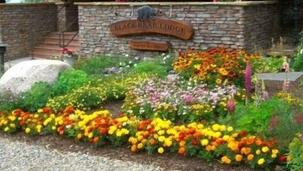 A stone wall with a wooden sign reading "BLACK BEAR LODGE." - Deluxe, Classic Mountain Condo | Near Chairlifts (Crested Butte)