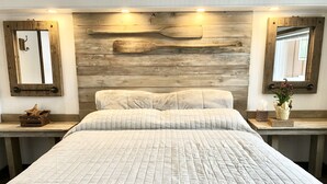 A large bed with a quilted bedspread, wooden headboard, and two bedside tables with a small plant and a tissue box. - 220’ WATERFRONT BEACH HOME ROCK RIVER WI PETS PIER POOLS FP FISHNG BOAT KAYAKS (Edgerton)