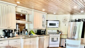 A kitchen with wooden cabinets, a large wooden table, a microwave, an oven, and a refrigerator. - 220’ WATERFRONT BEACH HOME ROCK RIVER WI PETS PIER POOLS FP FISHNG BOAT KAYAKS (Edgerton)