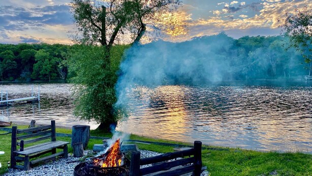 A lakeside view with a fire pit and wooden benches. - 220’ WATERFRONT BEACH HOME ROCK RIVER WI PETS PIER POOLS FP FISHNG BOAT KAYAKS (Edgerton)
