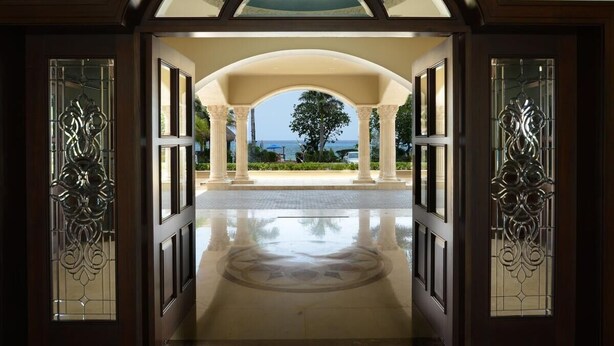 Una entrada con vista al mar, un corredor cubierto y paneles de vidrio decorativos.