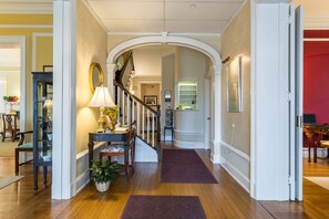 A hallway with wooden flooring, a staircase, and a red wall. - Stanton House Inn (Greenwich)