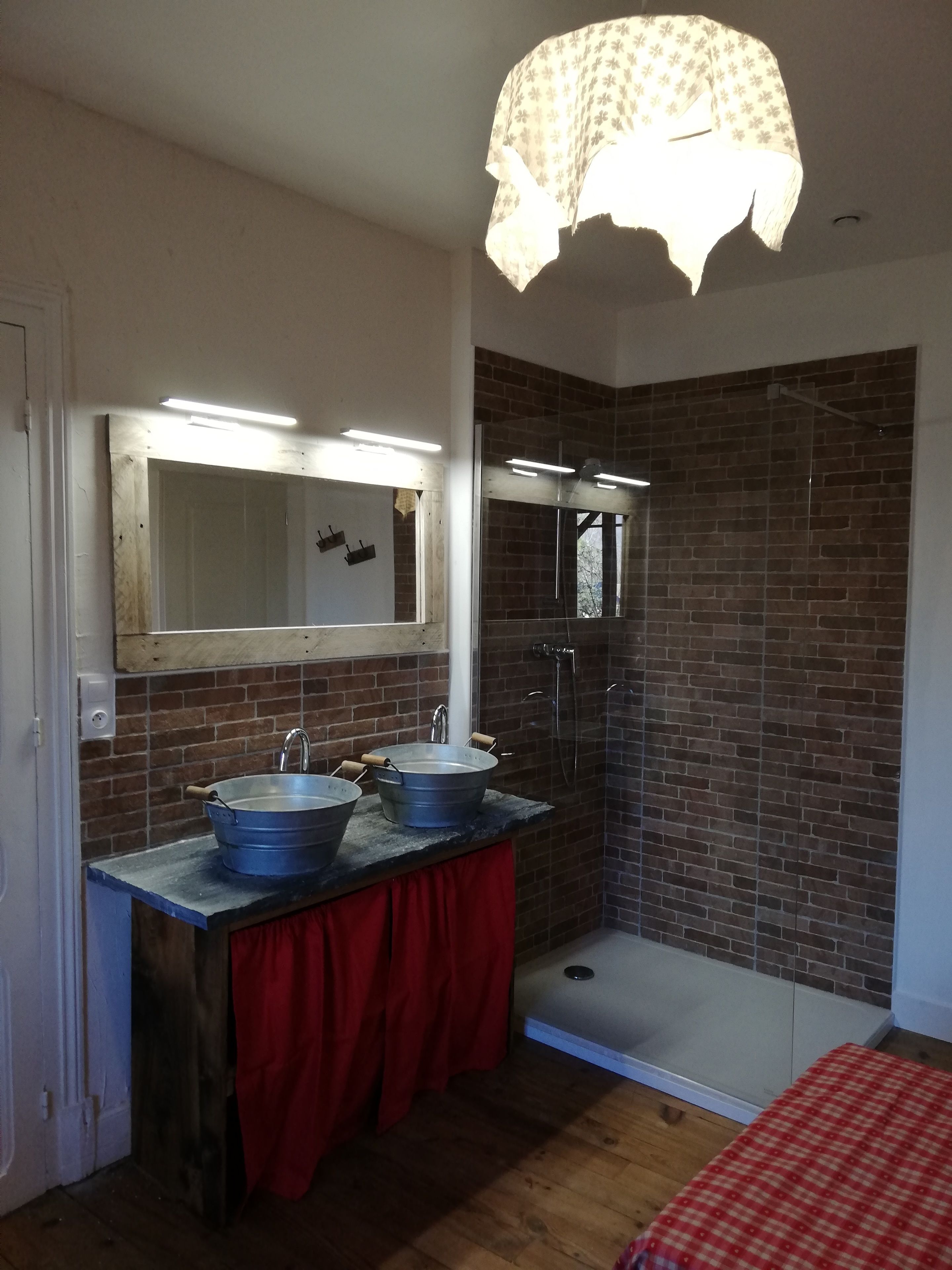 Een badkamer met twee wastafels, een douche en een spiegel met verlichting.