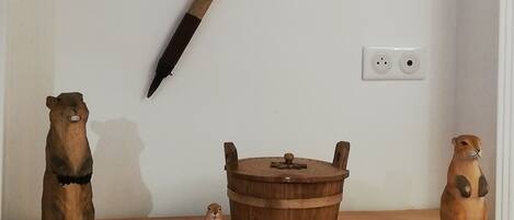 A wooden dresser with a rustic design, a wooden bucket, and two wooden figurines on top.