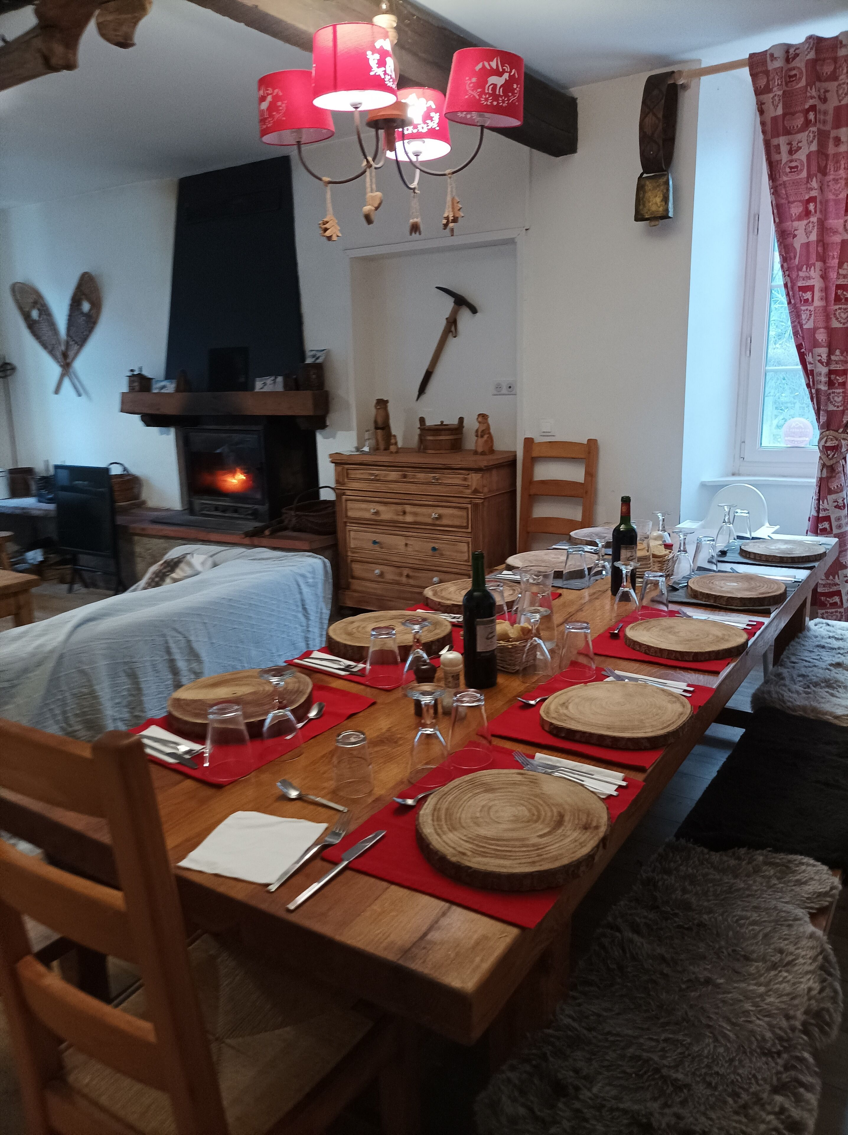 Un comedor con una larga mesa de madera dispuesta para una comida, una chimenea y una araña.