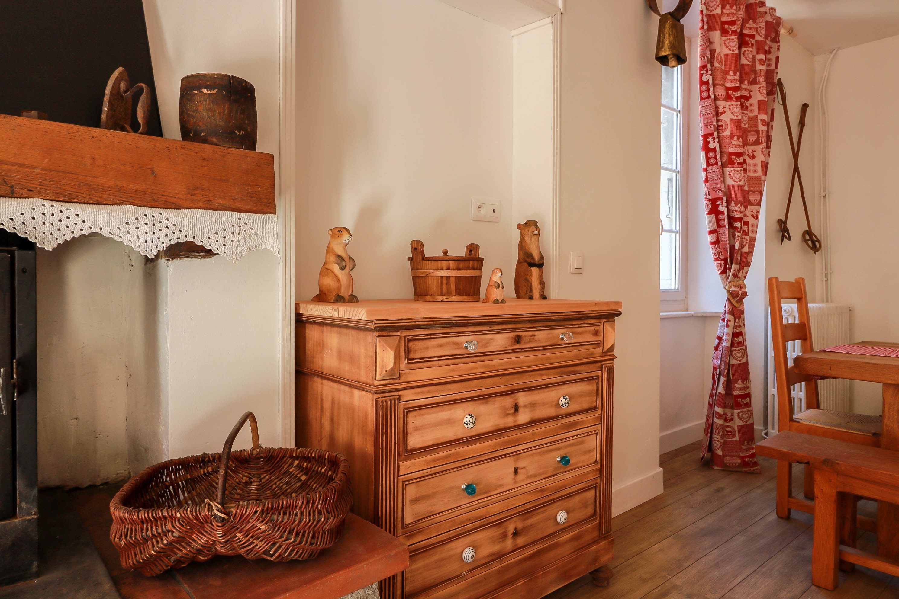 Un aparador de madera con cajones, una cesta de mimbre y una silla de madera.