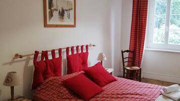 A bedroom with a bed, a chair, a window, and a picture on the wall.
