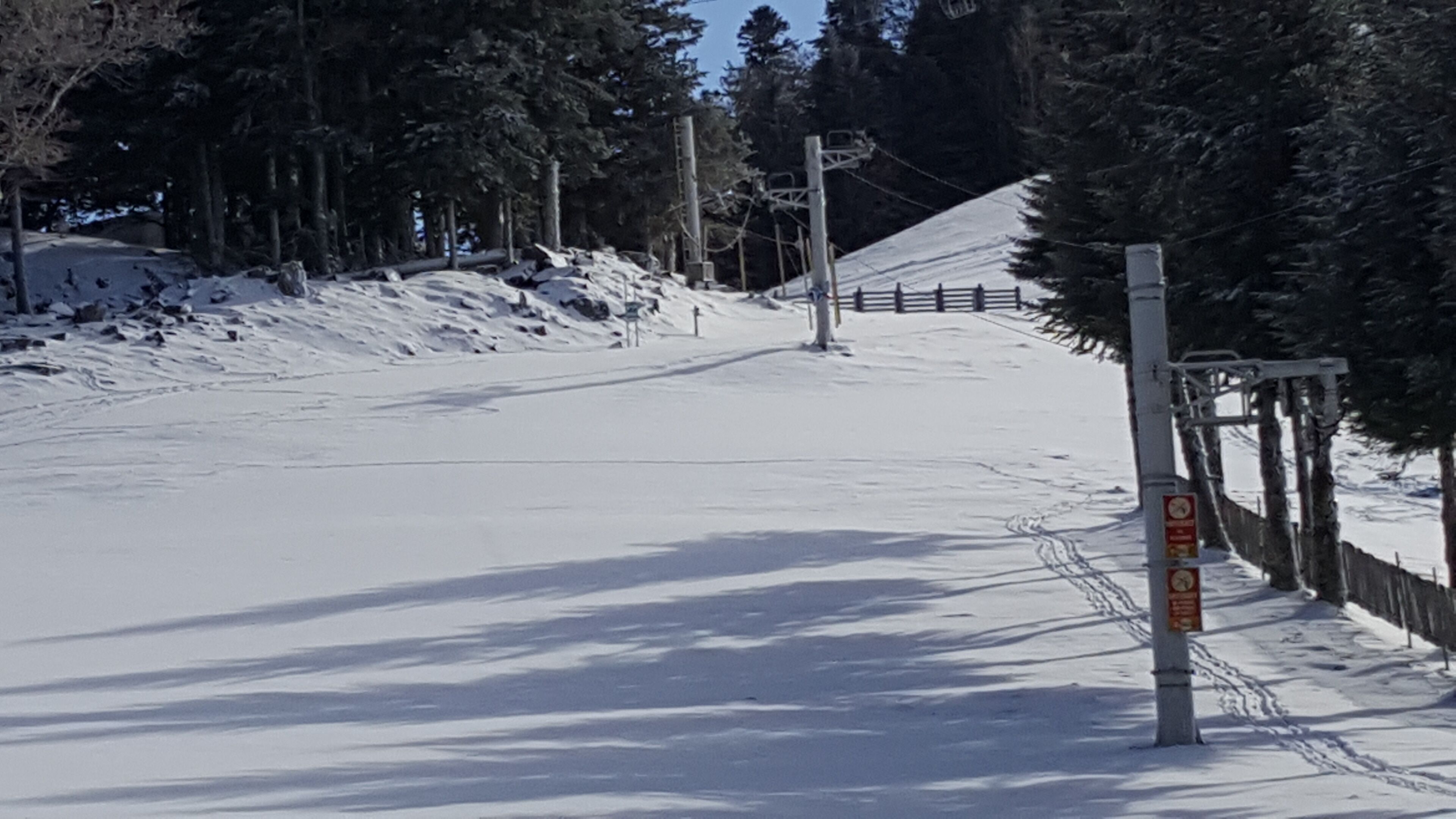 Pista da sci innevata con una recinzione in legno e un segnale.