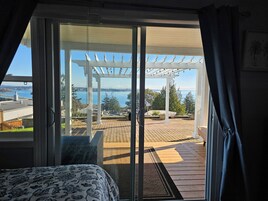 Una habitación con un gran ventanal corredero que da a un patio exterior con una pérgola y vistas al agua.