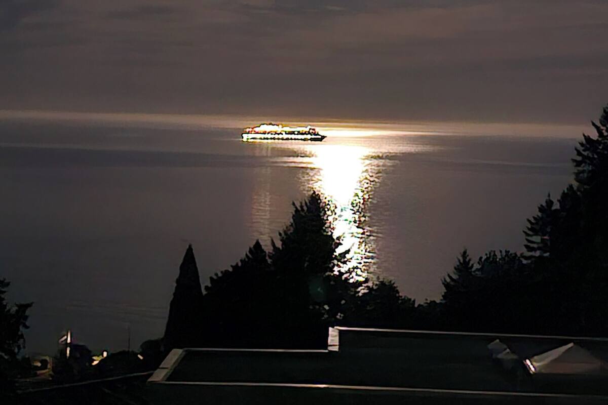 A sunset over a calm body of water with a cruise ship in the distance.