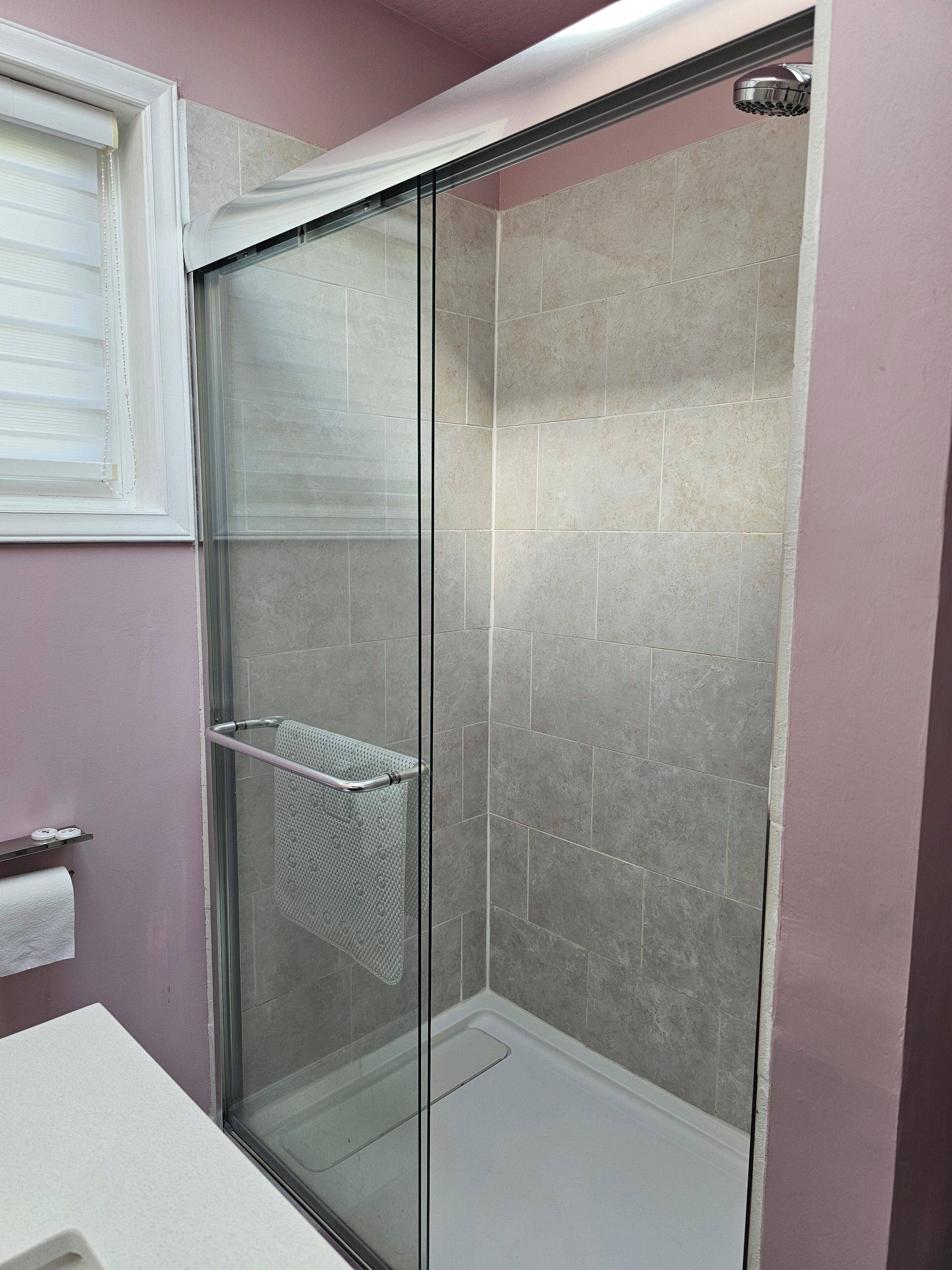 A glass-enclosed shower with a metal towel rack and a clear shower floor.