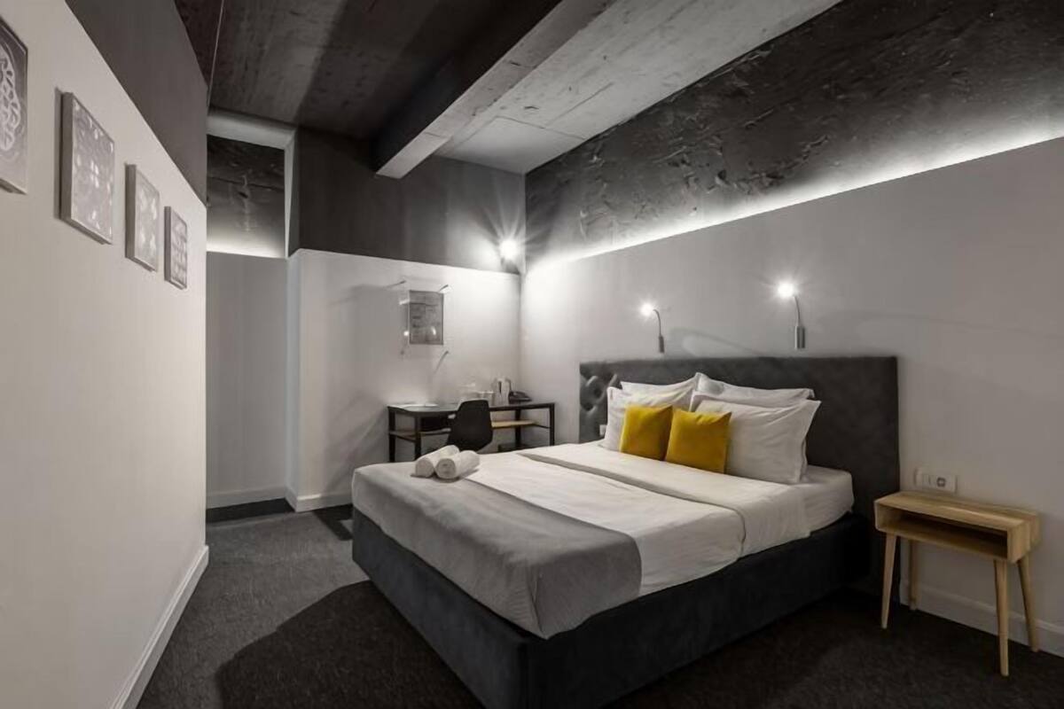 A modern bedroom with a bed, bedside tables, a desk, and a small table.