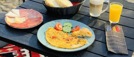 Une table dressée avec des aliments pour le petit-déjeuner, notamment des toasts, des œufs et du jus, posée sur un tapis à motifs.