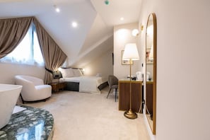 Une chambre d’hôtel moderne équipée d’un lit, d’un bureau, d’une chaise et d’un grand miroir.