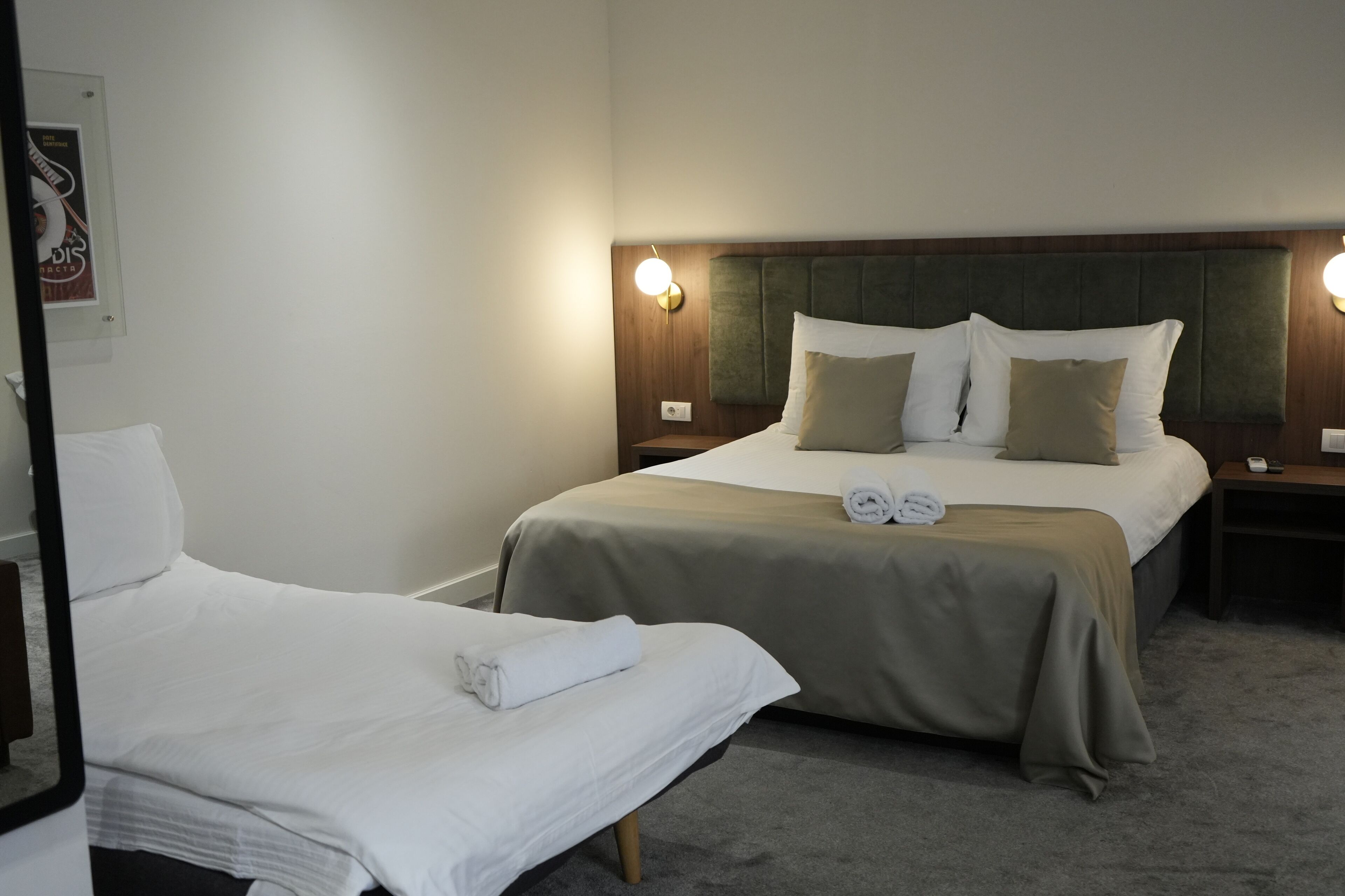 A hotel room with two beds, a wooden headboard, and a wall-mounted light fixture.