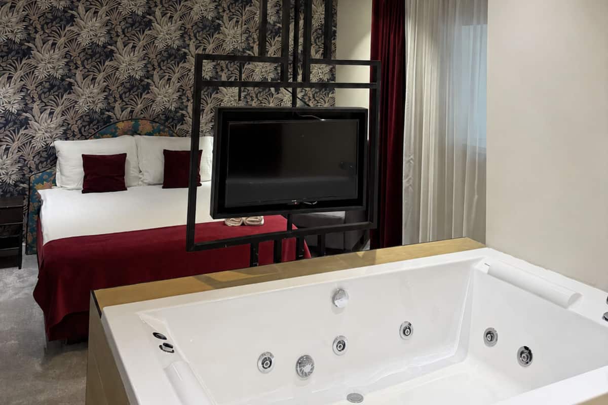 Une chambre d’hôtel avec un lit, une télévision et une baignoire.