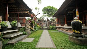 A traditional courtyard with a central pathway, surrounded by wooden structures and potted plants. - Awan Bali House (Ubud)