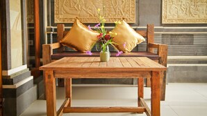 A wooden table with a vase of flowers and two cushions on a bench. - Awan Bali House (Ubud)