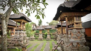 A courtyard with traditional Balinese architecture, including ornate statues and thatched-roof structures. - Awan Bali House (Ubud)