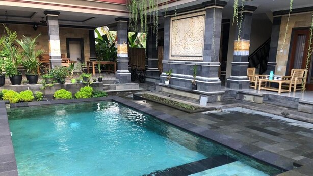 A rectangular pool with clear water, surrounded by stone steps and potted plants. - Awan Bali House (Ubud)