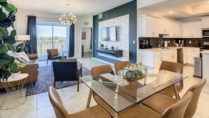 Una sala de estar moderna con una mesa de comedor de vidrio, sillas de cuero marrón y un ventanal que ofrece vistas al exterior.