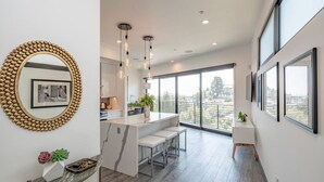 Una cucina moderna con isola centrale, illuminazione a sospensione e ampie finestre che offrono vista sulla città.