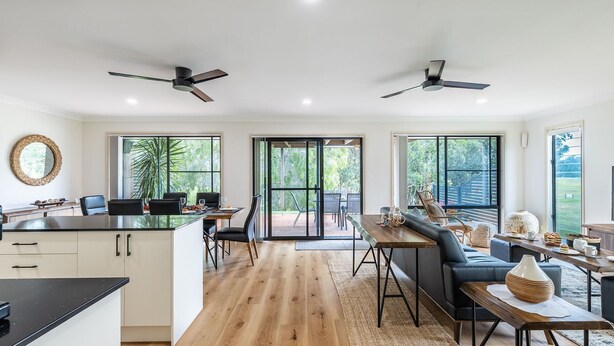 Eine moderne Küche mit Essbereich, großen Fenstern und Deckenventilatoren.