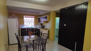 A compact kitchen with a dining area, featuring a refrigerator, microwave, and a dining table with chairs. - Aanola Villas A3 Quietude Residence (Castries)