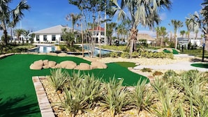 Un campo de golf con putting green, jardines circundantes y una zona de piscina.