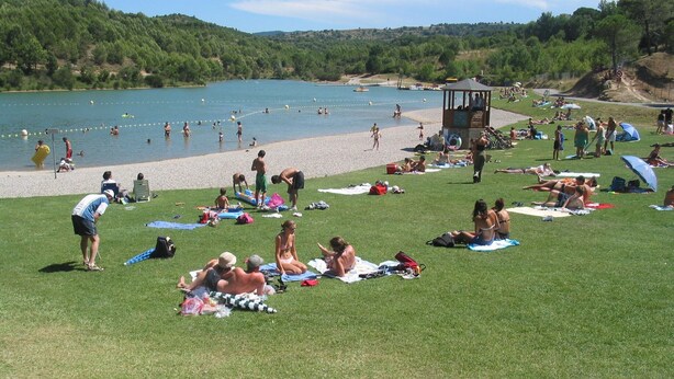 A grassy area with people sunbathing and swimming in a lake. - Stylish modern villa with private heated pool in scenic Trebes, near Carcassonne (Trèbes)