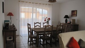 A dining area with a wooden table and chairs, a vase with flowers, a lamp, and a painting on the wall. - Stylish modern villa with private heated pool in scenic Trebes, near Carcassonne (Trèbes)