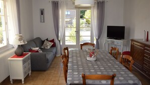 Un salon comprenant un canapé, une table à manger, des chaises, un téléviseur et une lampe.