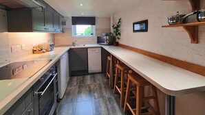 A modern kitchen with a central island, built-in appliances, and a small window. - Garden Apartment- perfectly located (Shanklin)