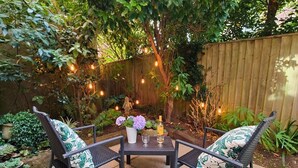 An outdoor patio with two wicker chairs, a small table, and a bottle of champagne. - Garden Apartment- perfectly located (Shanklin)