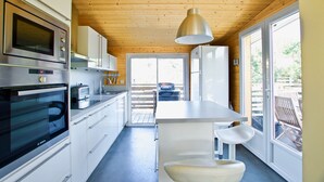 Een moderne keuken met roestvrijstalen apparatuur, witte kastjes en een groot raam voor natuurlijk licht.