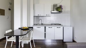 A modern kitchen with white cabinets, a black countertop, and a stainless steel sink. There is a small potted plant on the countertop.