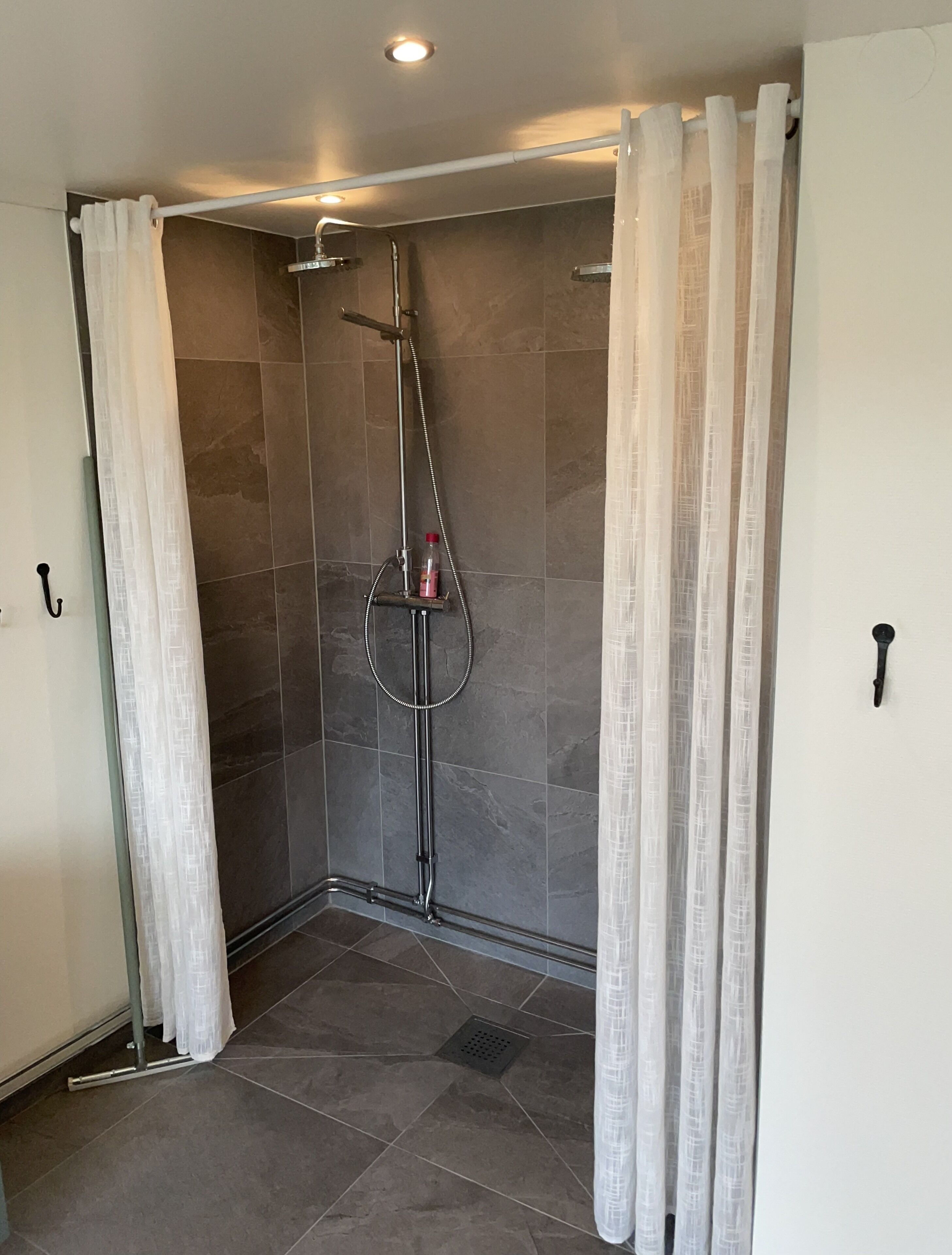 Un espace douche doté d’une porte en verre, d’un pommeau de douche à main et d’un robinet mural.